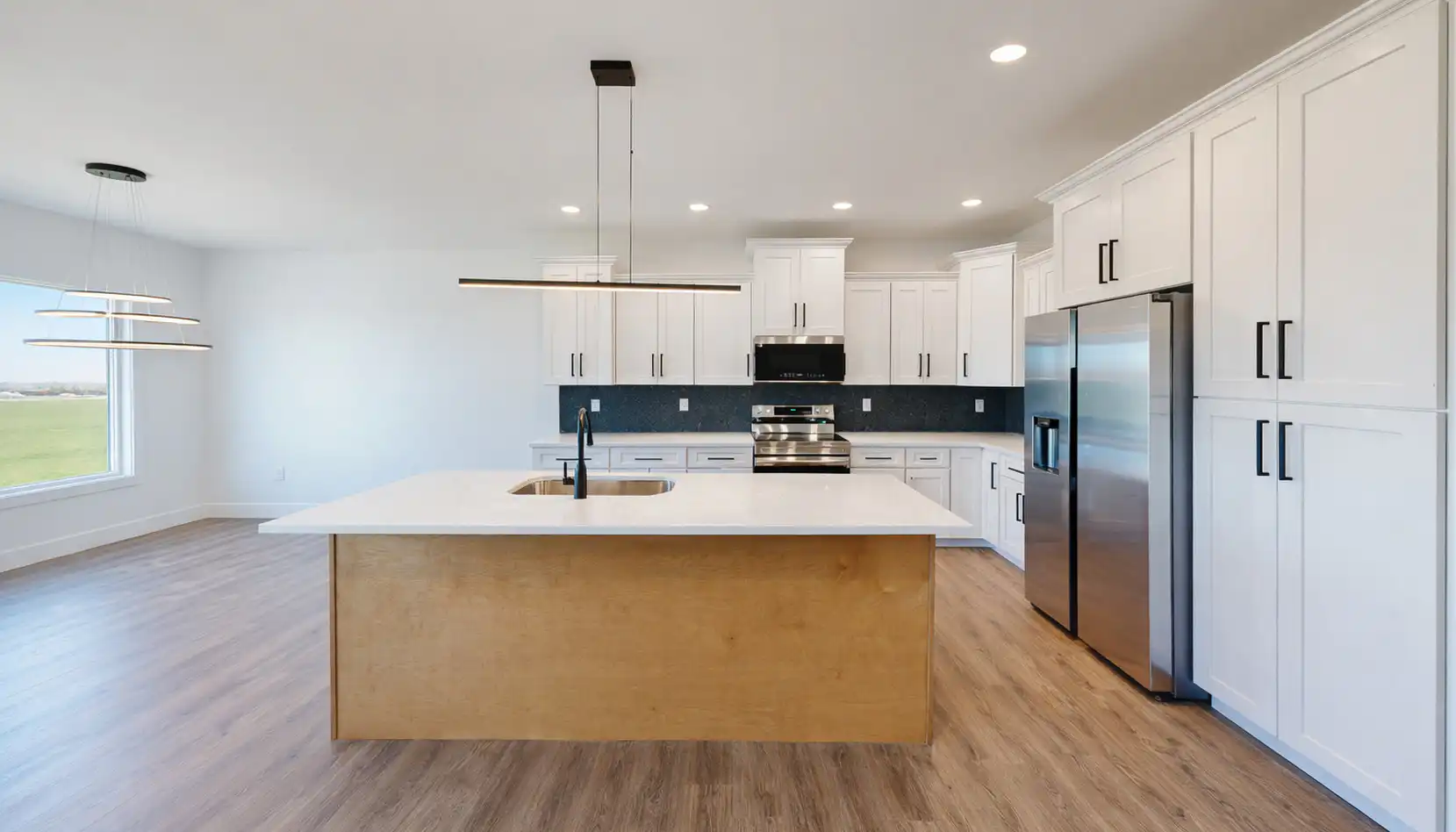 Modern Leo kitchen with white cabinets, stainless appliances, and large wood island with sink.