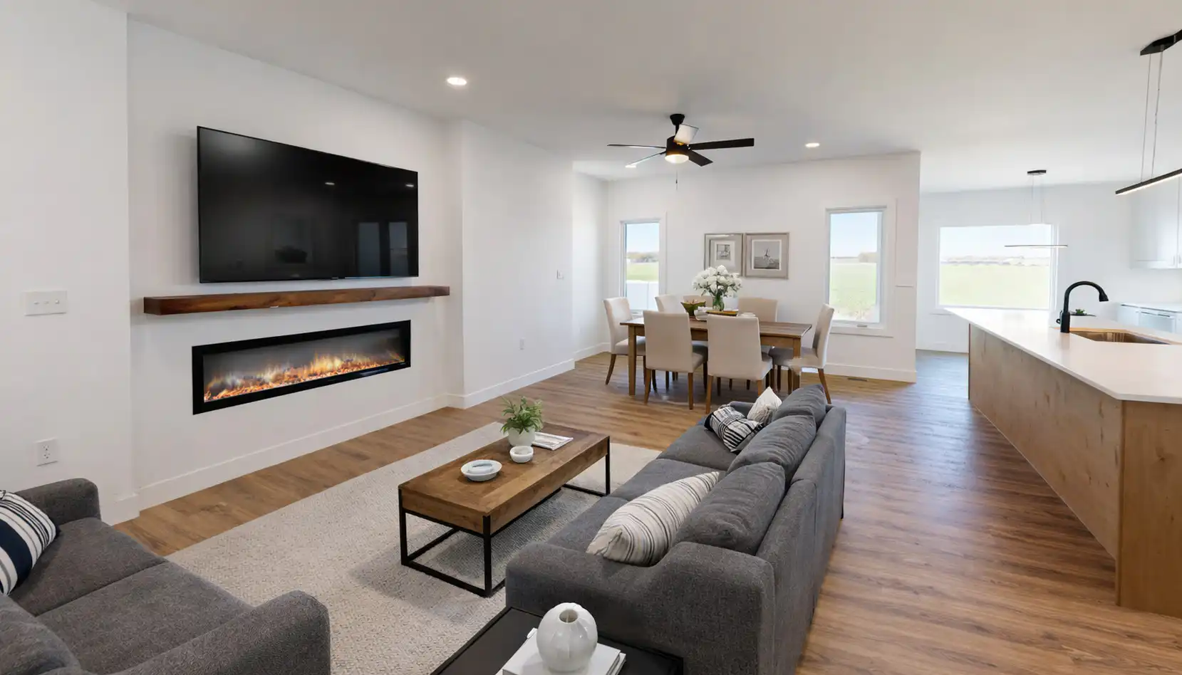 Leo-inspired open-concept living room with gray sofas, linear fireplace, dining area, and kitchen island.