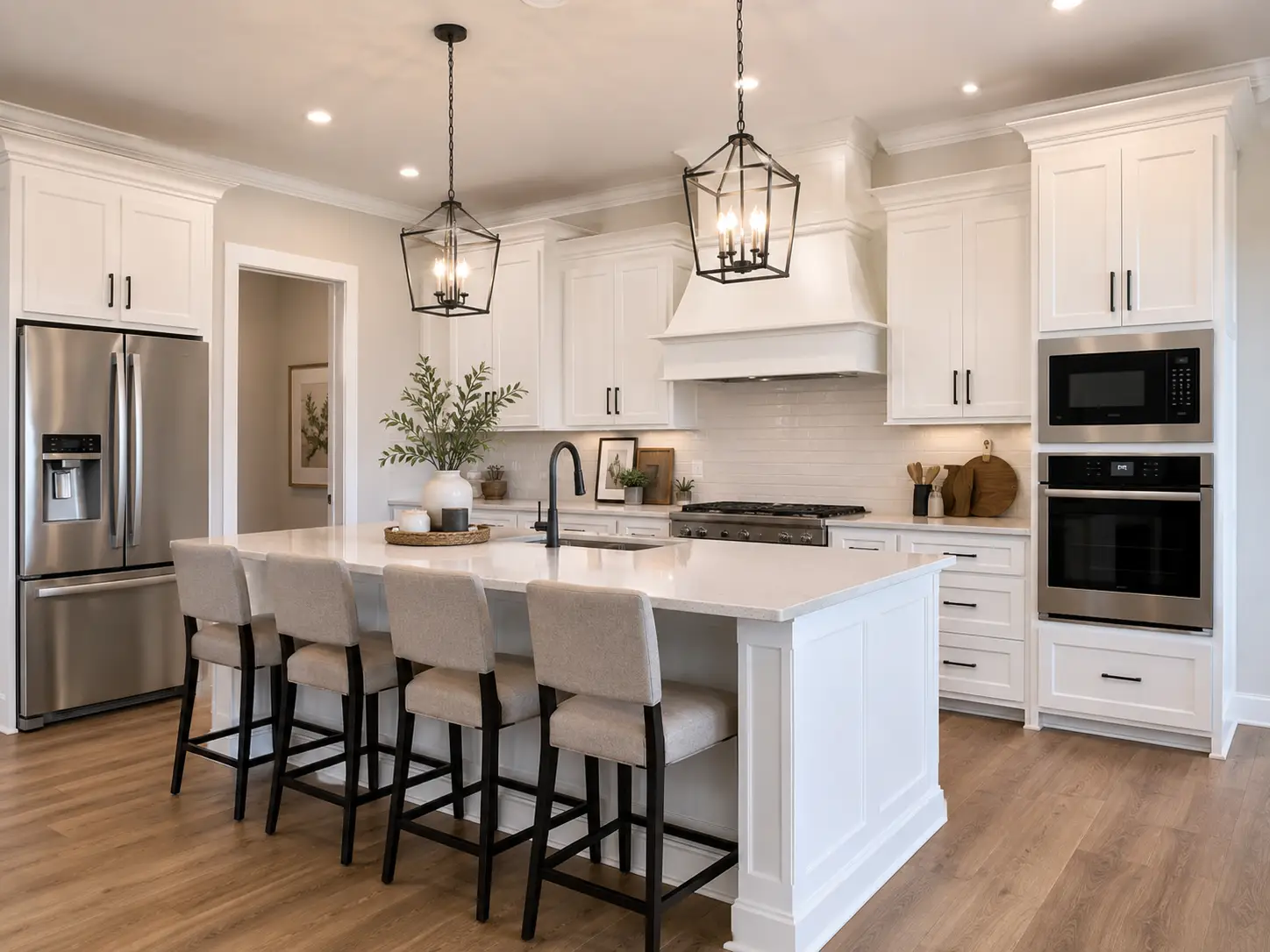 Bright kitchen gallery with white shaker cabinets, large island, black pendants, and stainless steel appliances.